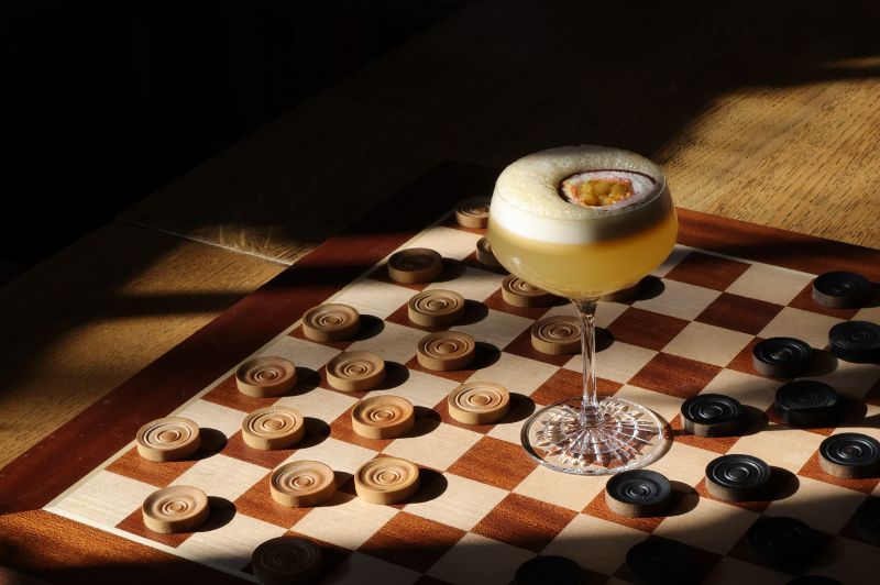 Creative cocktail served on a checkerboard at the Library Bar of Brasserie Ambassade in Amsterdam