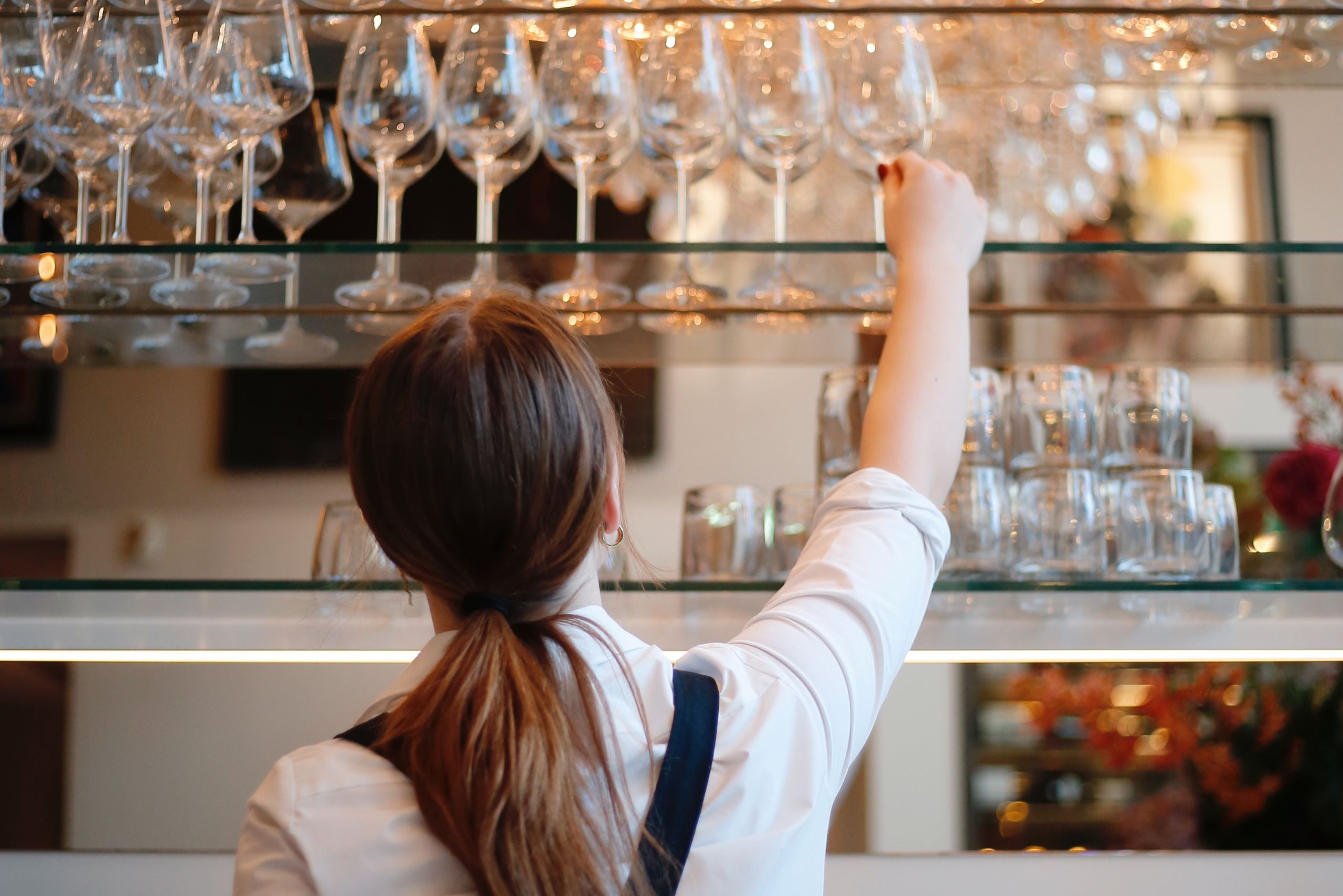 Career staff member placing a wine glass behind the bar at Brasserie Ambassade in Amsterdam